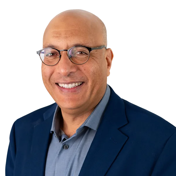 Smiling bald man wearing round glasses, a navy blazer, and a gray collared shirt