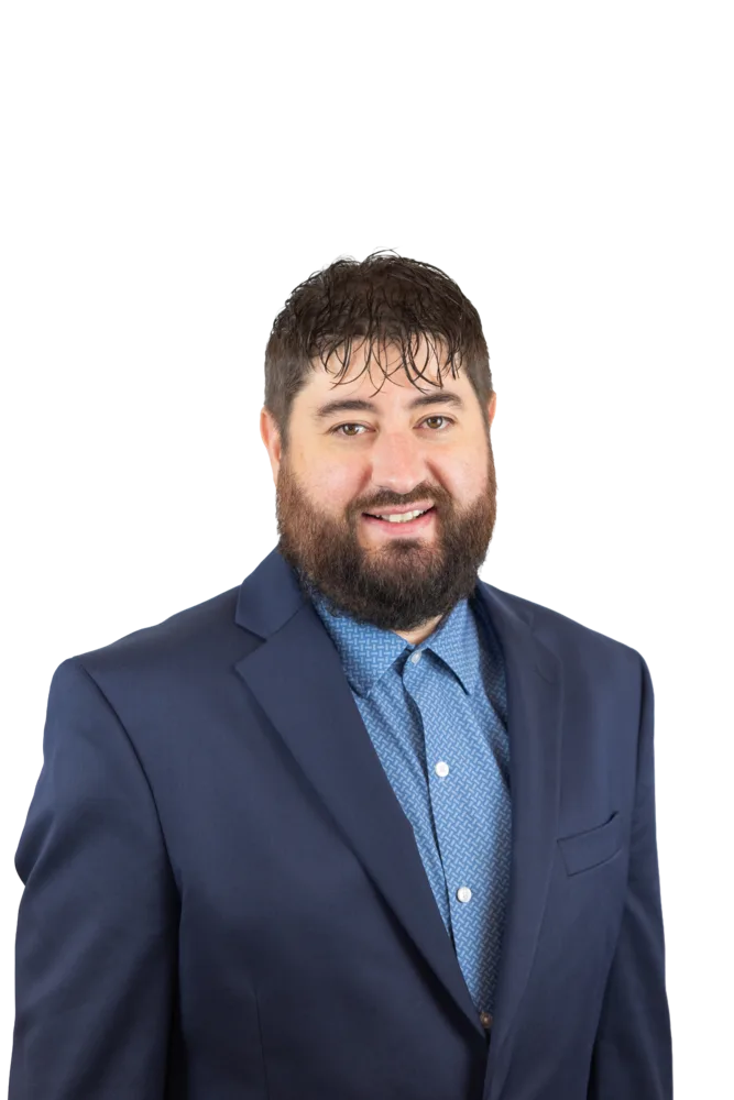 Bearded man smiling in a navy suit and blue patterned shirt
