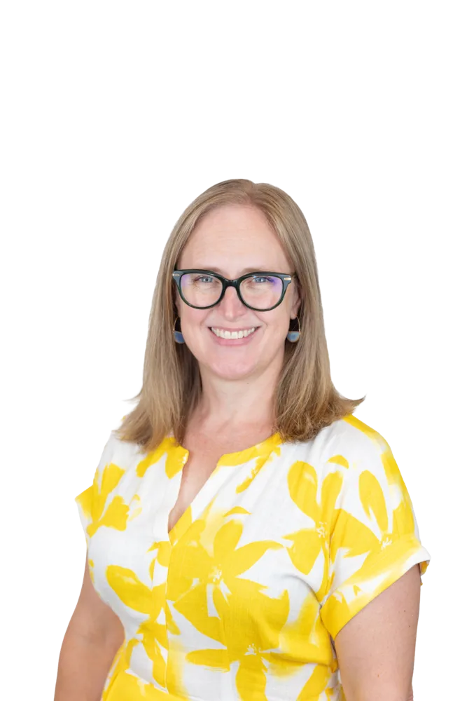 Smiling woman wearing glasses, blue earrings, and a white blouse with a yellow floral pattern