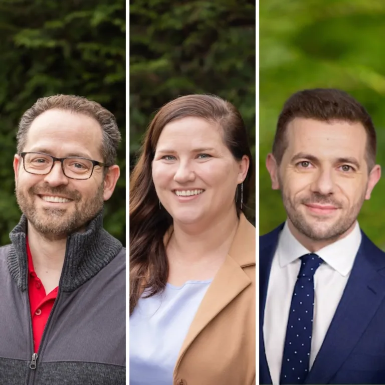 Three side-by-side headshots outdoors: left, a smiling man with glasses in a gray zip sweater over a red polo; center, a smiling woman with long brown hair in a tan coat over a light top; right, a smiling man in a navy suit with a white shirt and navy polka-dot tie, all set against blurred greenery.