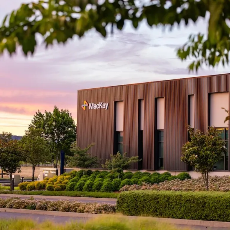 Mackay-branded modern office building surrounded by landscaped gardens at sunset