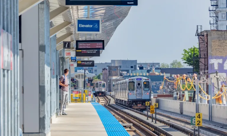CTA elevated train station platform with two trains, accessibility and direction signs, and a passenger waiting