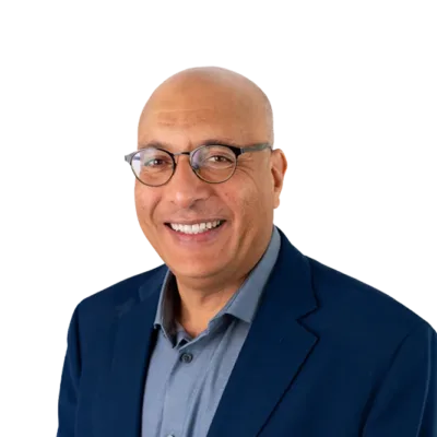 Smiling bald man wearing glasses, a blue blazer, and a gray collared shirt