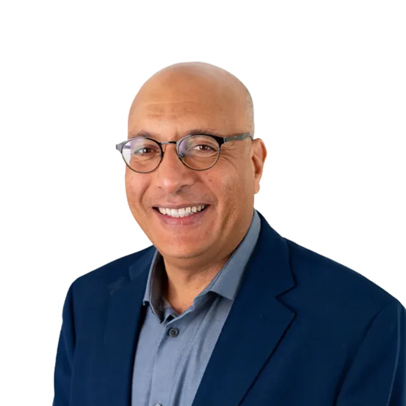 Smiling bald man wearing glasses, a blue blazer, and a gray collared shirt