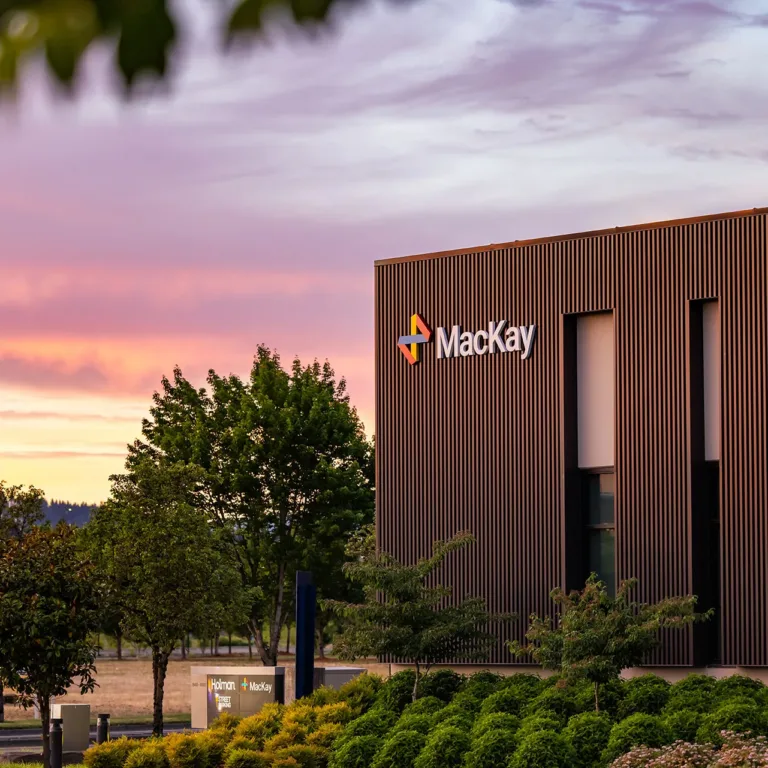 Mackay building on 184th Avenue at sunset, with landscaped grounds and street signs for Holman Road and Bennington Drive
