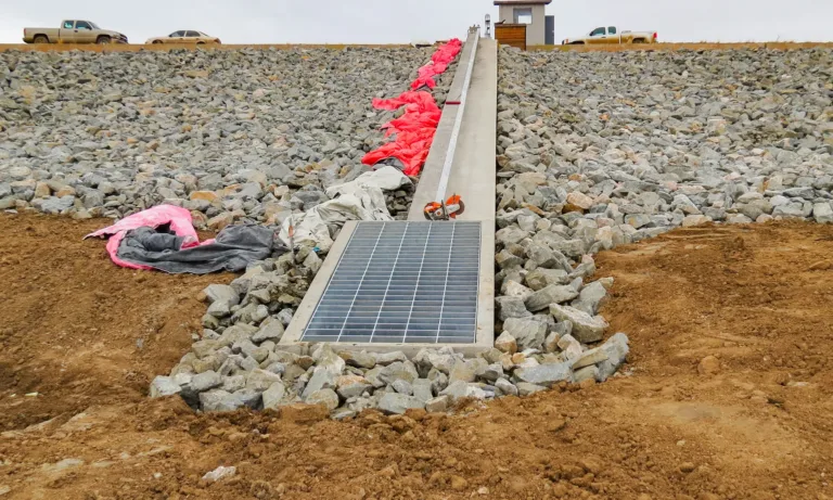 Solar panel installed on a rocky embankment, with construction materials and a small utility structure above