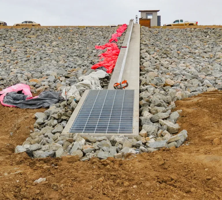 Solar panel installed on a rocky embankment, with construction materials and a small utility structure above