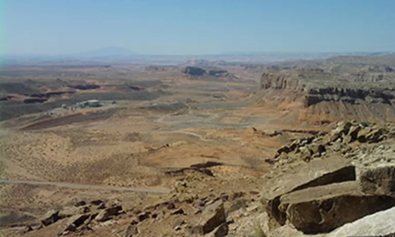 Expansive arid volcanic landscape with rugged lava cliffs and rocky terrain beneath a clear blue sky