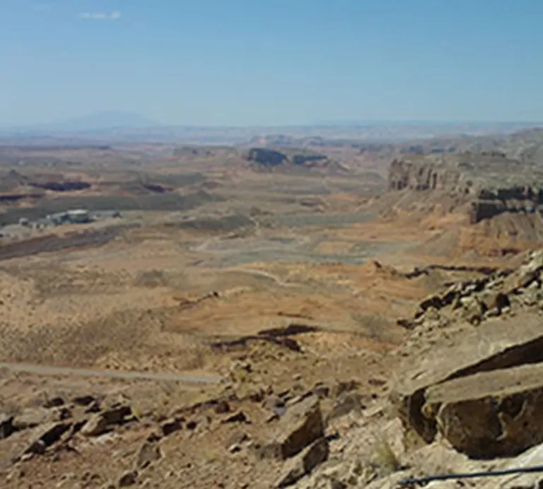 Expansive arid volcanic landscape with rugged lava cliffs and rocky terrain beneath a clear blue sky