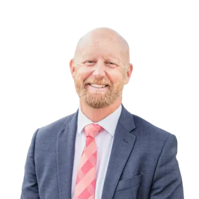 Smiling bald man with a beard wearing a blue suit, white shirt, and pink striped tie