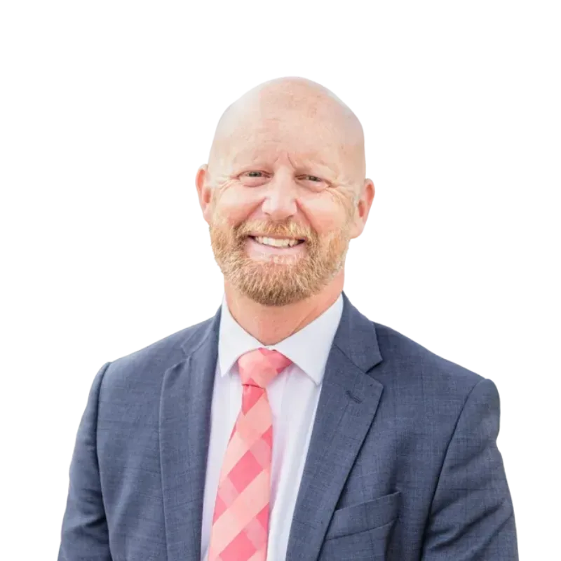 Smiling bald man with a beard wearing a blue suit, white shirt, and pink striped tie
