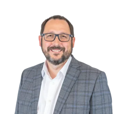 Smiling bearded man wearing glasses, a white shirt, and a gray plaid blazer