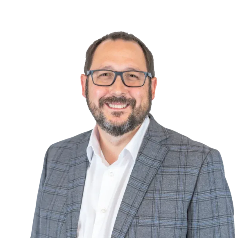 Smiling bearded man wearing glasses, a white shirt, and a gray plaid blazer