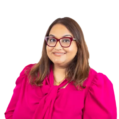 Woman wearing glasses and a bright pink blouse, smiling at the camera
