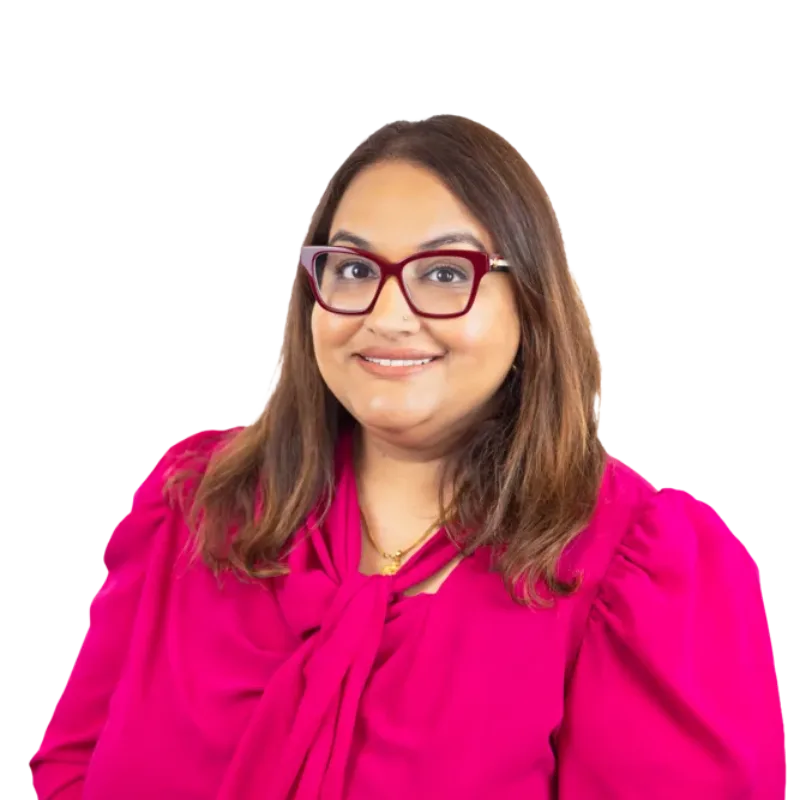 Woman wearing glasses and a bright pink blouse, smiling at the camera