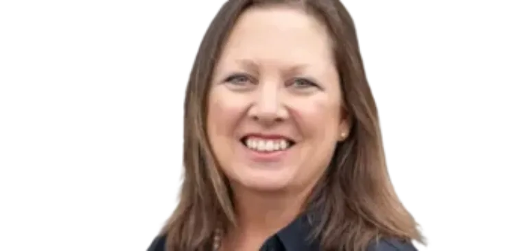 Smiling woman with shoulder-length brown hair wearing a dark blouse and pearl necklace