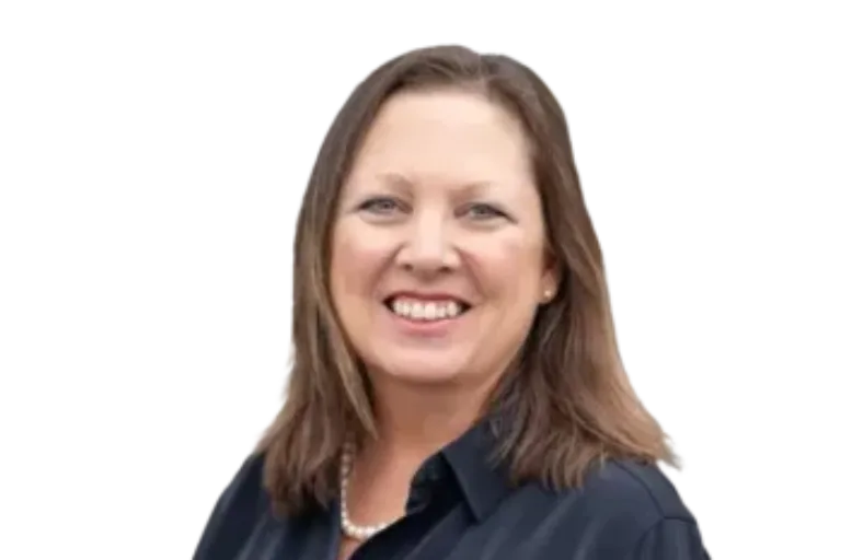 Smiling woman with shoulder-length brown hair wearing a dark blouse and pearl necklace