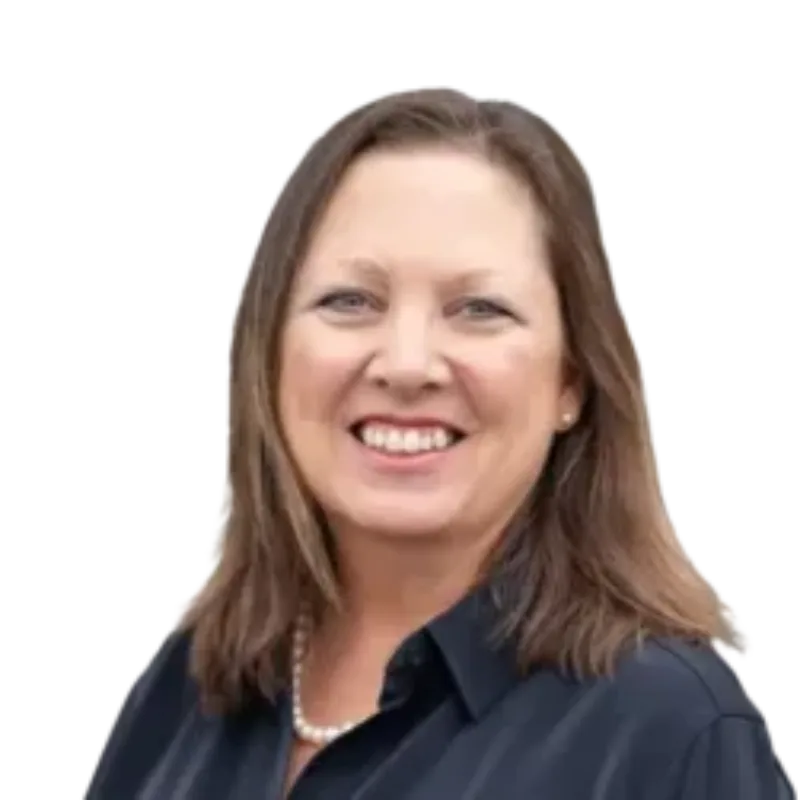 Smiling woman with shoulder-length brown hair wearing a dark blouse and pearl necklace