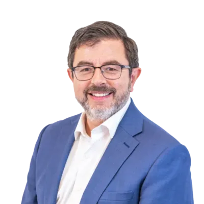 Smiling bearded man wearing glasses, a blue suit, and white shirt
