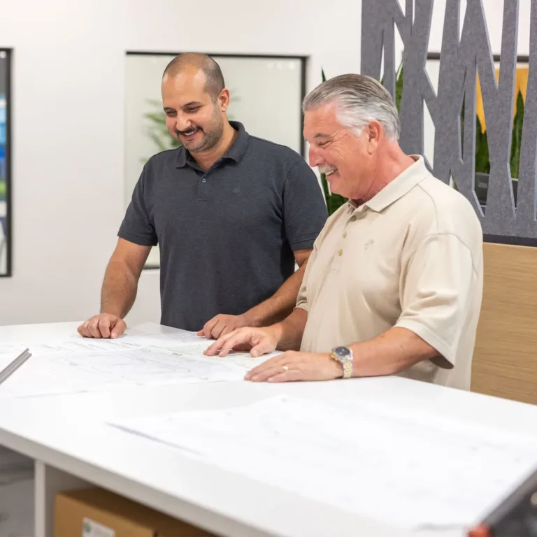Two men review architectural plans at a table