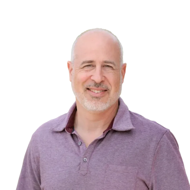 Smiling bald man with a gray goatee wearing a purple polo shirt