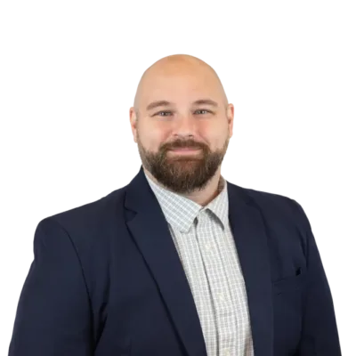 Bearded bald man in a navy blazer and checked shirt, smiling against a transparent background