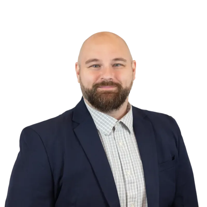 Bearded bald man in a navy blazer and checked shirt, smiling against a transparent background