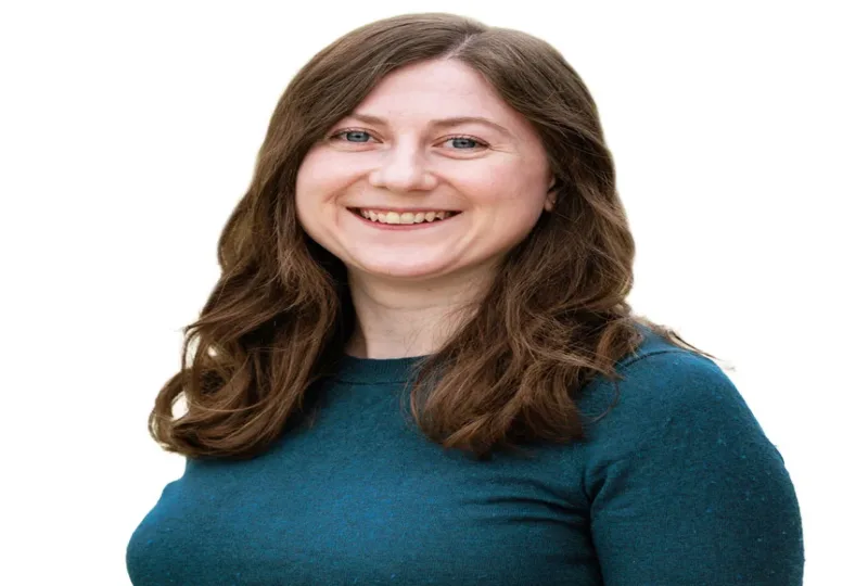 Smiling woman with long brown hair wearing a teal sweater