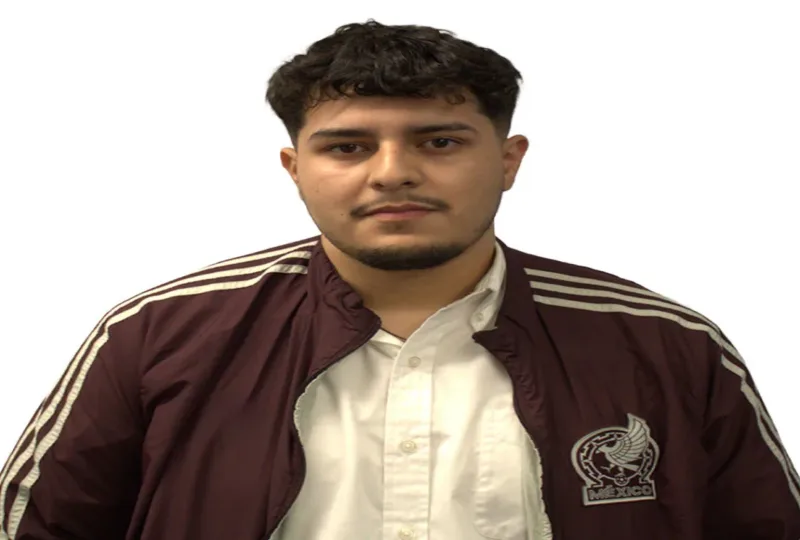 Man wearing a maroon striped track jacket over a white shirt, facing the camera