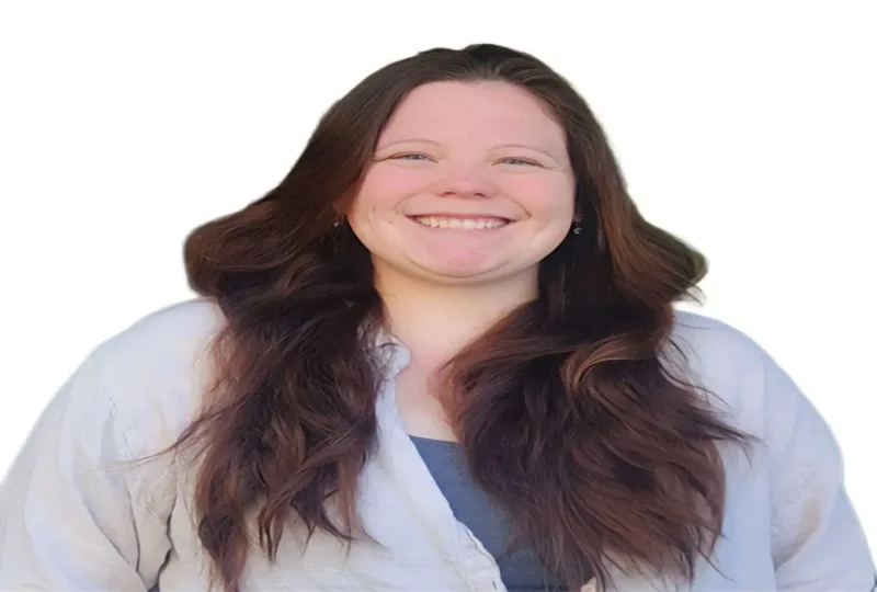 Smiling woman with long brown hair wearing a white coat over a blue shirt