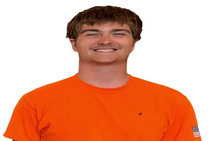 Smiling young man wearing an orange shirt with a small logo and an American flag patch on the sleeve