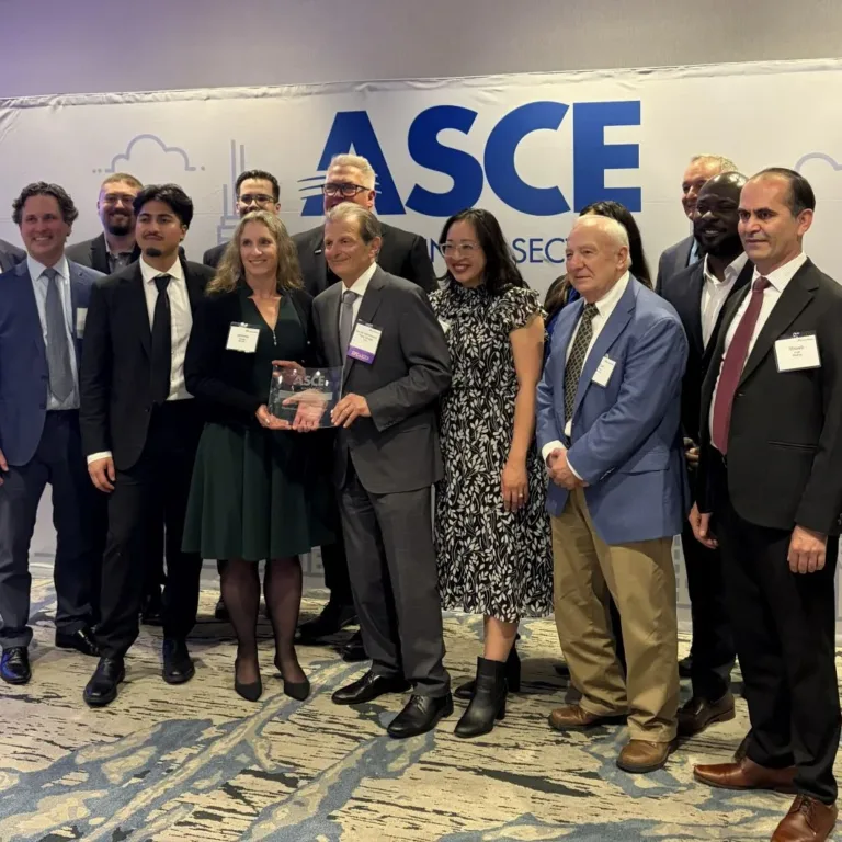 Group of professionals posing at an ASCE event, with two people holding an ASCE award in front of the event backdrop