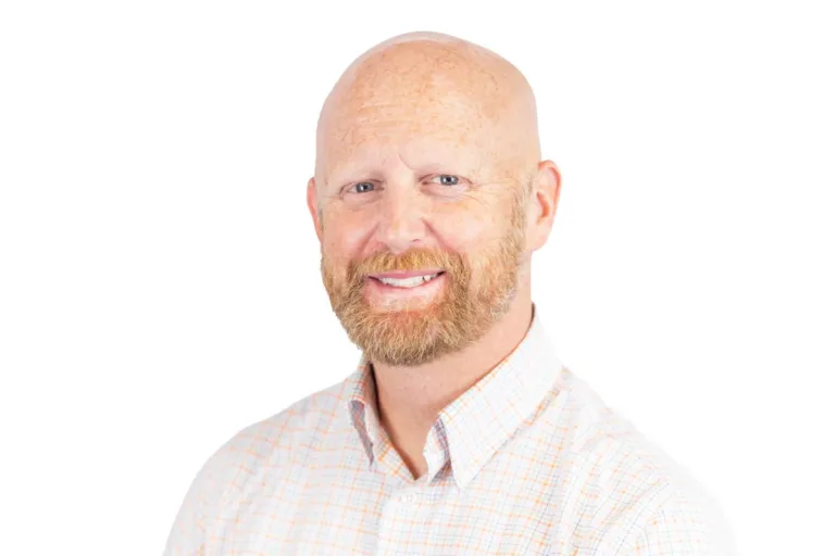 Smiling bald man with a reddish beard wearing a light plaid button-up shirt